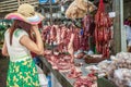 Female customer buying meat at butcherÃ¢â¬â¢s shop, variety of meat, pork, beef, chicken, ribs and chinese sausage. Phsa Thmei Market